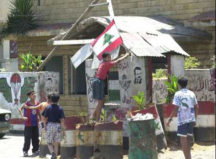 A little boy placing a Lebanese flag on an evacuated Syrian military base